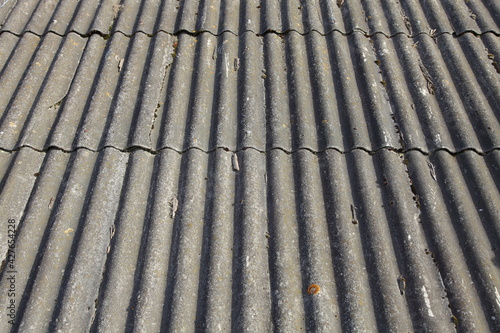 Gray aged dry roofing slate roof - vertical old asbestos profile texture background in perspetive close up, village style
