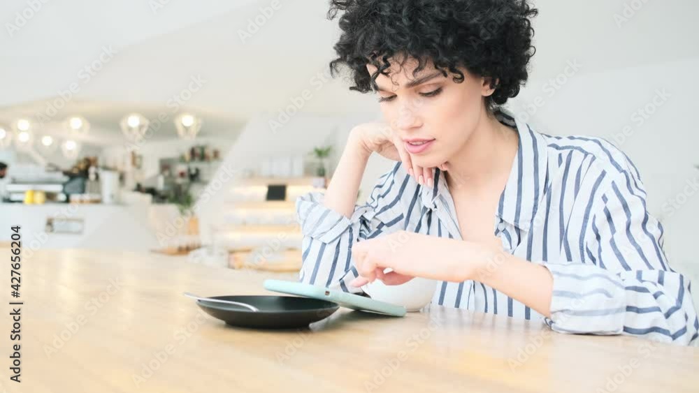 A good-looking woman is using her smartphone while sitting in the cafe A good-looking woman is using her smartphone while sitting in the cafe