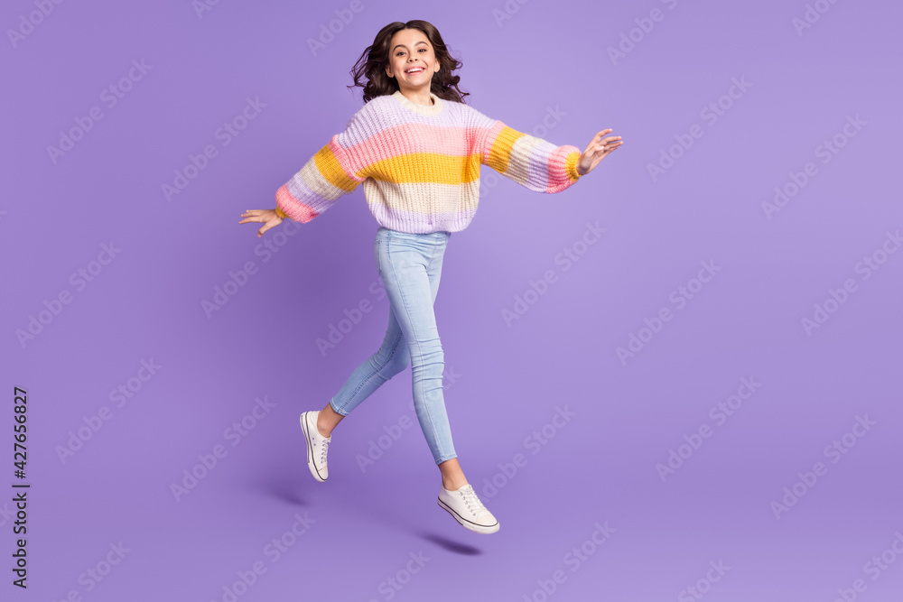 Full size photo of young happy excited girl go walk in air wear knitted sweater and pants isolated on purple color background