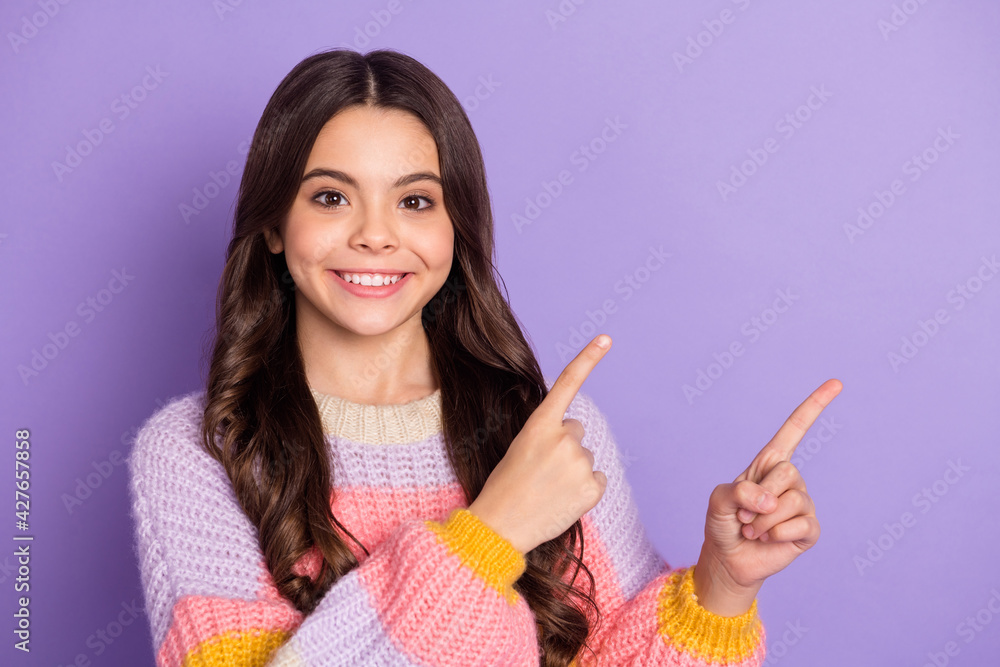 Photo of young girl happy positive smile indicate fingers empty space ad promo choose decision isolated over purple color background Photo of young girl happy positive smile indicate fingers empty space ad promo choose decision isolated over purple color background