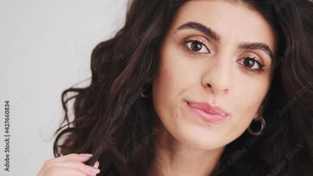 The close-up view of a pensive woman's face winding her hair around her finger The close-up view of a pensive woman's face winding her hair around her finger