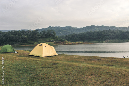 The yellow tent stands in the grasslands overlooking the lake