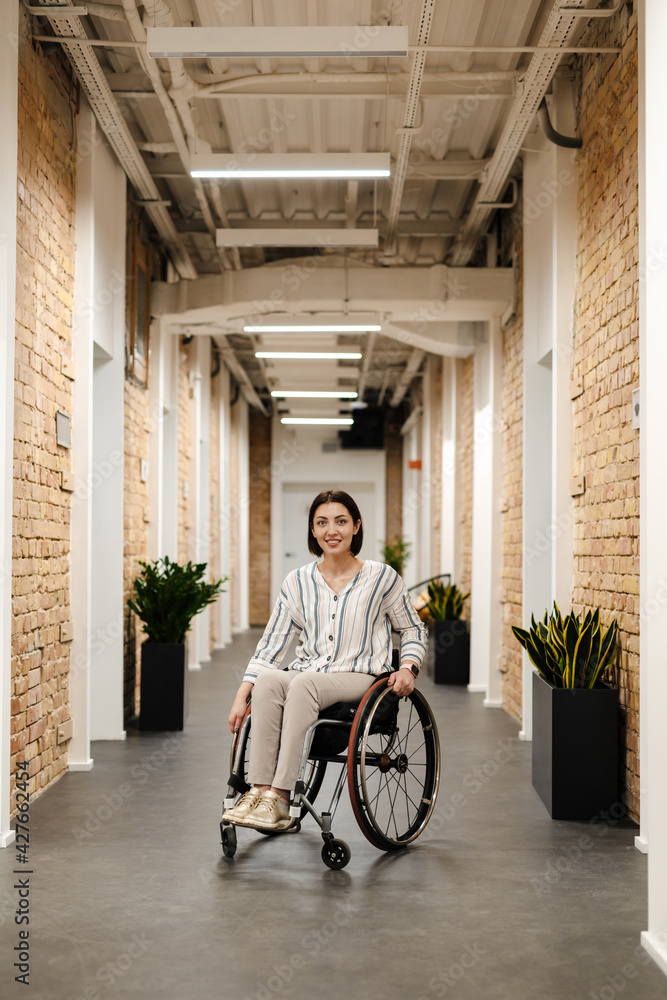 White young woman smiling while sitting in wheelchair at office White young woman smiling while sitting in wheelchair at office