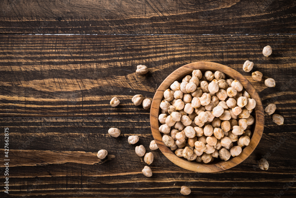 Chickpeas in white bowl at wooden kitchen table. Chickpeas in white bowl at wooden kitchen table.