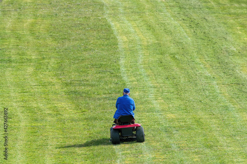man in blue mowing a lawn