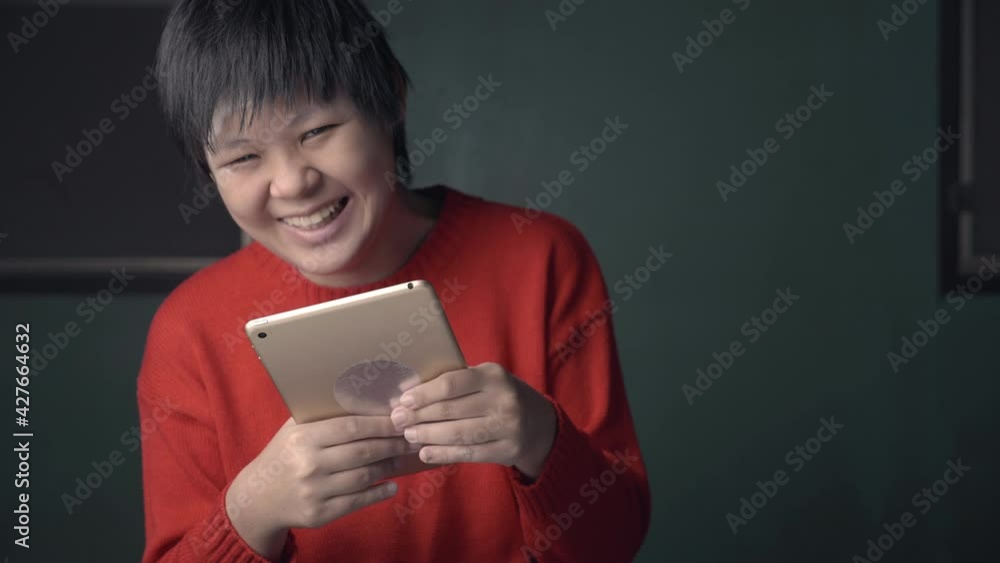 Asian child is autistic looking tablet computer for learning, autism girl watching tablet for development of brain and education, health care of disabilities with adhd and communication concept. Asian child is autistic looking tablet computer for learning, autism girl watching tablet for development of brain and education, health care of disabilities with adhd and communication concept.