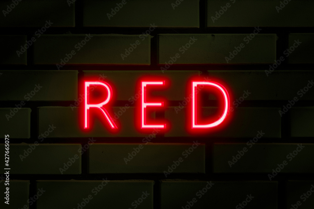 Neon inscription -Red on a green brick wall. Neon inscription -Red on a green brick wall.