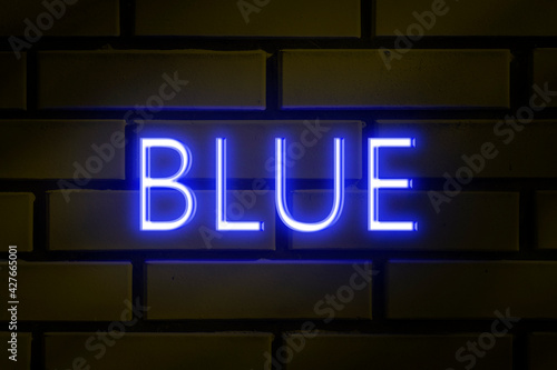 Neon sign - BLUE on a yellow brick wall