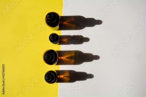 A set of bottles for cosmetic products on a yellow-white background. The containers are standing, and the shadow falls on the background. Hard light. Top view, copy space
