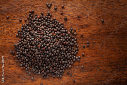 Macro close-up of Organic Black mustard seed (Brassica nigra)  on wooden top background. Pile of Indian Aromatic Spice. Top view