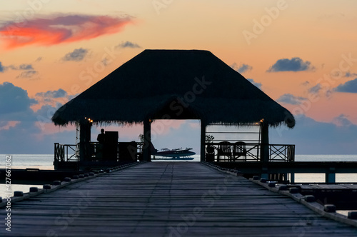seaplane on the maldivian lagoon at sunset. View across a hut on a pier