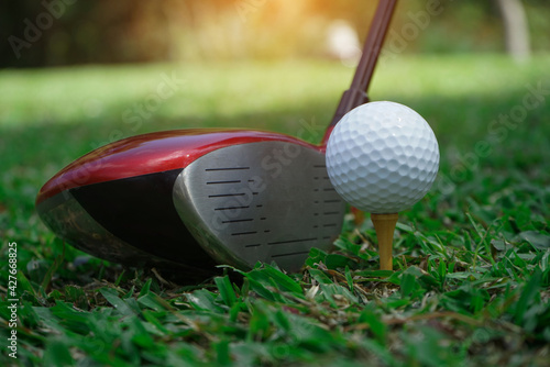 Golf club and golf ball close up in grass field with sunset. Golf ball close up in golf coures at Thailand.