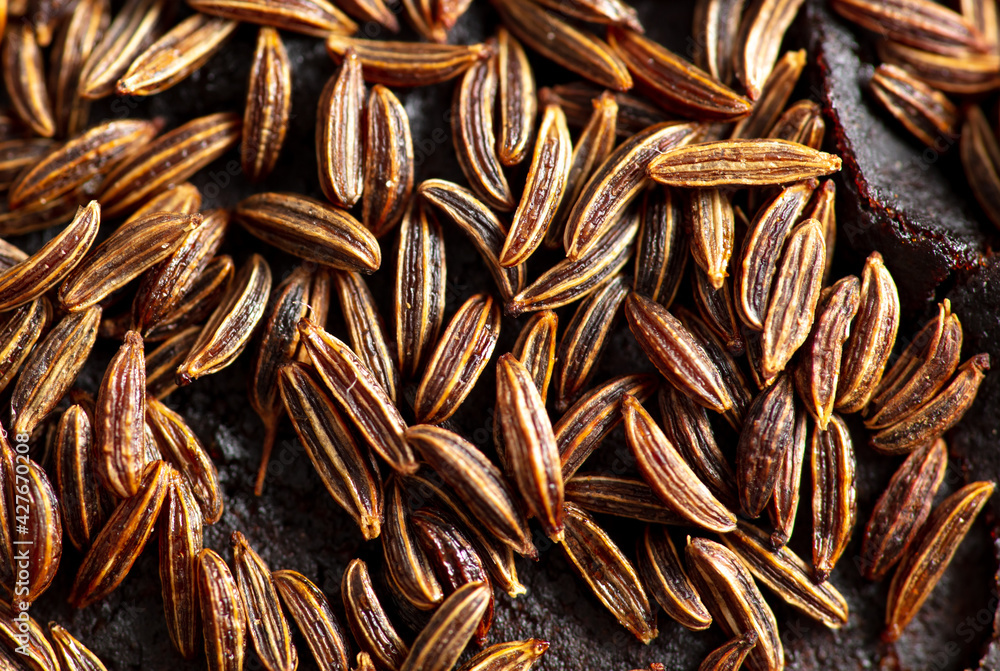 Cumin seeds on rye bread as background.