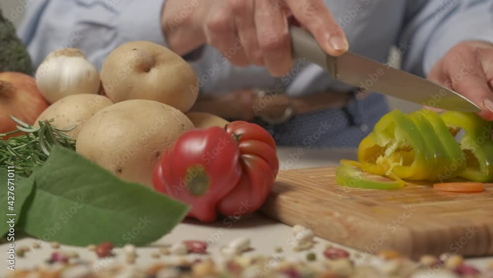 Woman cutting pepper vegetable in home kitchen. Preparing vegan vegetarian meal, healthy nutrition, Mediterranean diet. Woman cutting pepper vegetable in home kitchen. Preparing vegan vegetarian meal, healthy nutrition, Mediterranean diet.