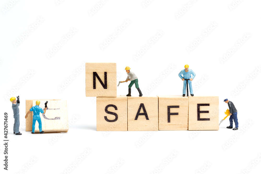 Miniature  people worker team changing The word unsafe turned into safe on white background