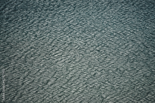 Texture of dark green calm water of lake. Meditative ripples on water surface. Nature minimal background of deep green lake. Natural backdrop of clear dark turquoise water. Full frame of lake fragment