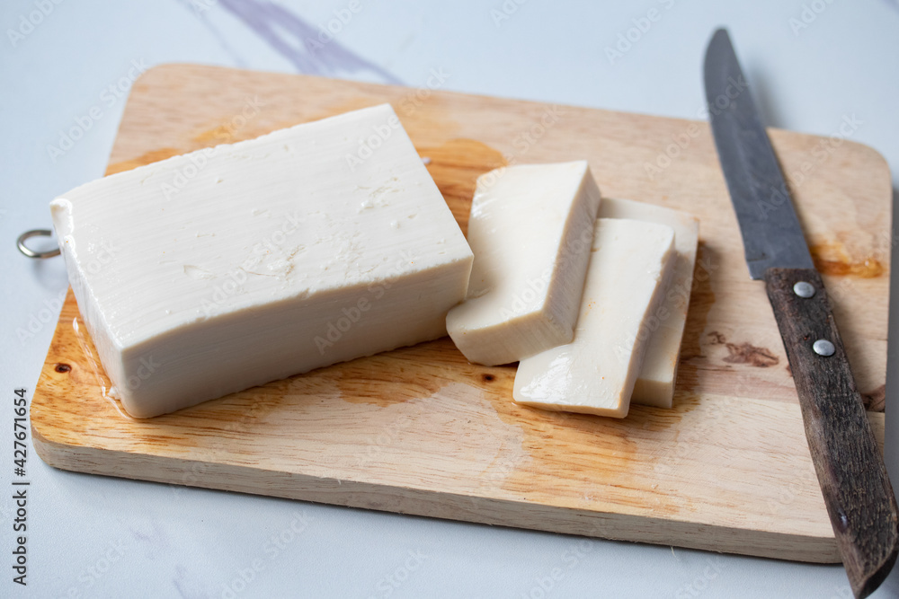 White square tofu cubes On a wooden cutting board and a knife