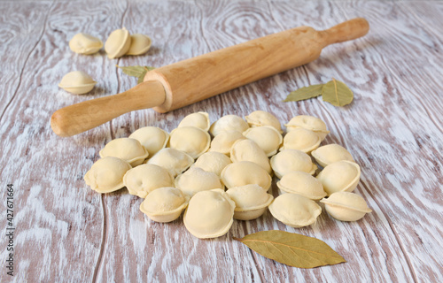 Frozen dumplings and wooden rolling pin on a wooden table, close up