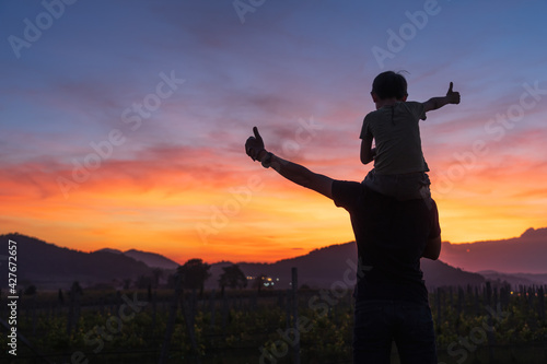 Father and son thumbs up for the beautiful sunset and sky at twilight silhouette concept.