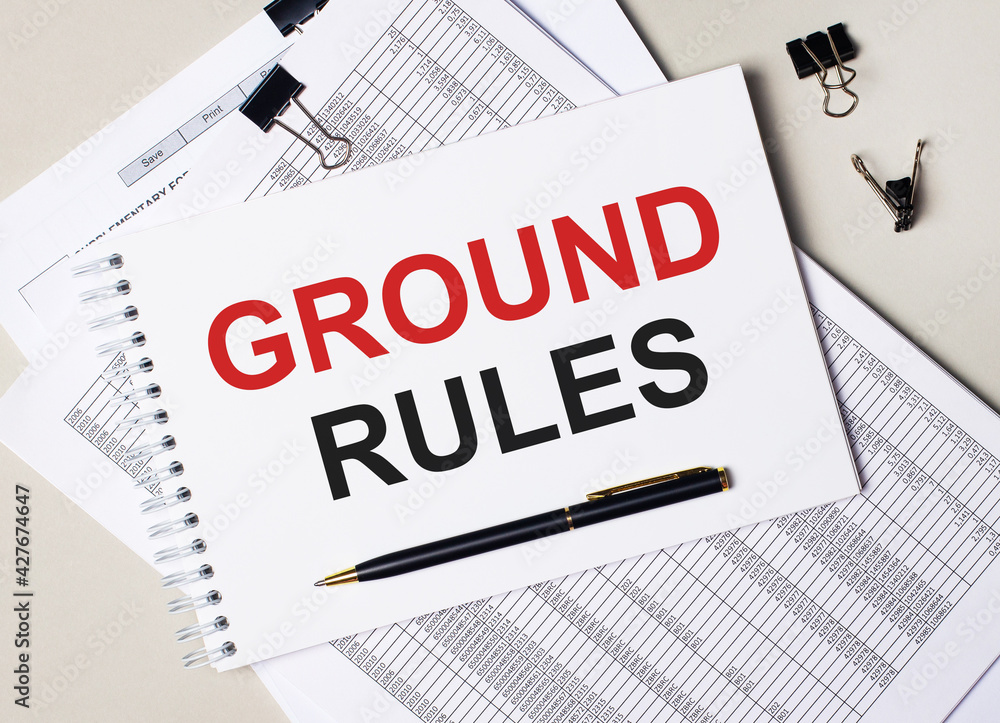 On the desktop there are documents, pen, black paper clips and a notebook with the text GROUND RULES. Business concept On the desktop there are documents, pen, black paper clips and a notebook with the text GROUND RULES. Business concept