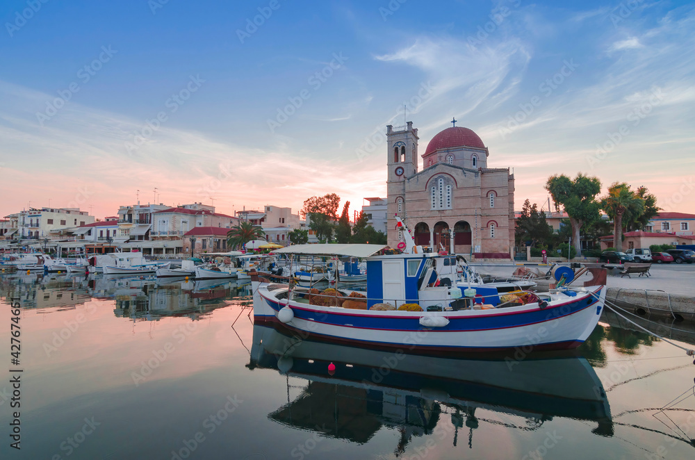 Port of charming Aegina town with yachts and fishermen boats docked in Aegina island, Saronic gulf, Greece, at sunset.