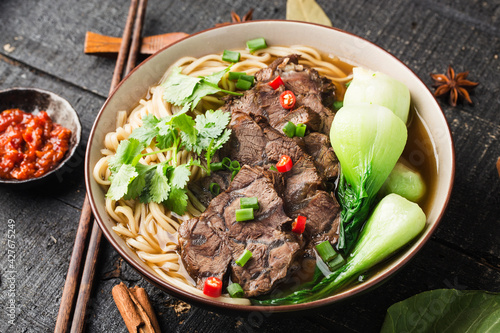 Canvas Print Spicy red soup beef noodle in a bowl on wooden table