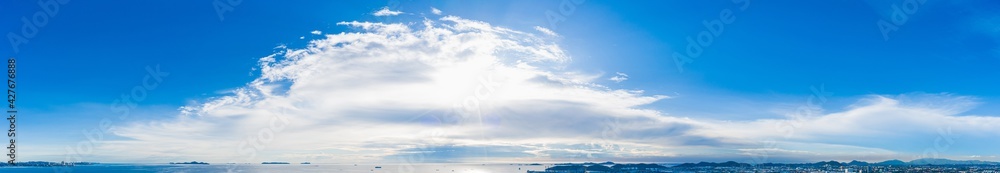 Blue sky background with white clouds, rain clouds and sunlight with lens flare on rainy season or spring day. Panorama view 