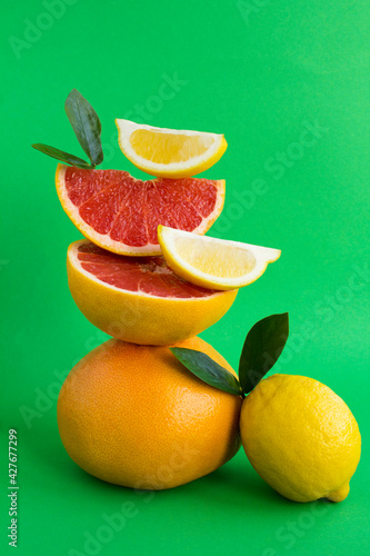 Pyramid of grapefruit and lemon in balance  on the green background.Close-up. Location vertical.