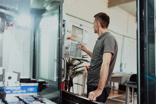 a man puts an aluminum piece on a cnc machine and prepares a processing machine..