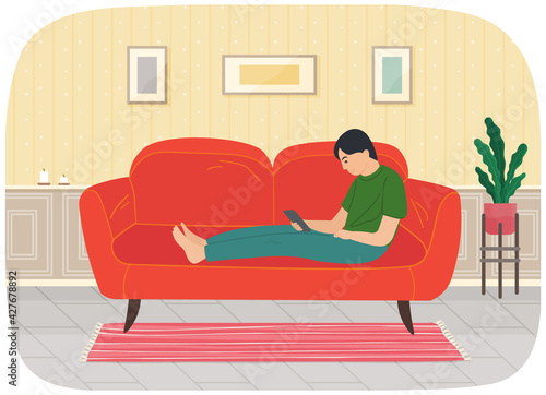 Young man sitting on couch with tablet, studying remotely, watches social media, serfing Internet