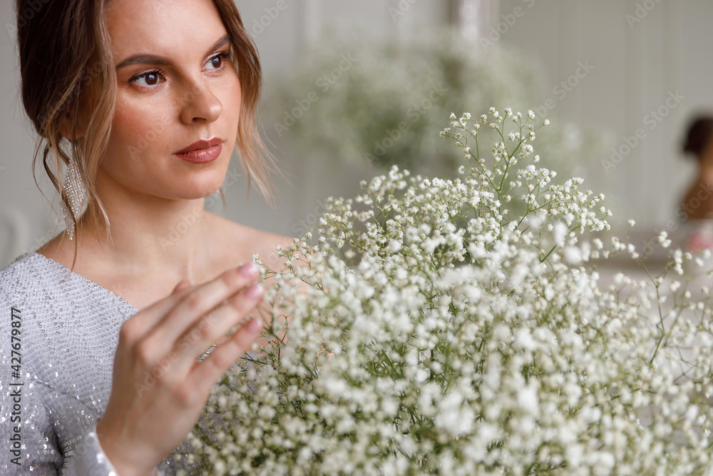 Close up portrait of a beautiful young woman with brown eyes, with a bouquet of white gypsophila flowers. Place for your text, copyspace. The concept of beauty and youth. Pensive mood, sadness Close up portrait of a beautiful young woman with brown eyes, with a bouquet of white gypsophila flowers. Place for your text, copyspace. The concept of beauty and youth. Pensive mood, sadness