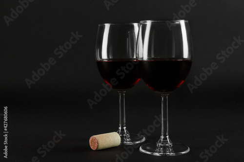 Two glass glasses of red wine on a black homogeneous background