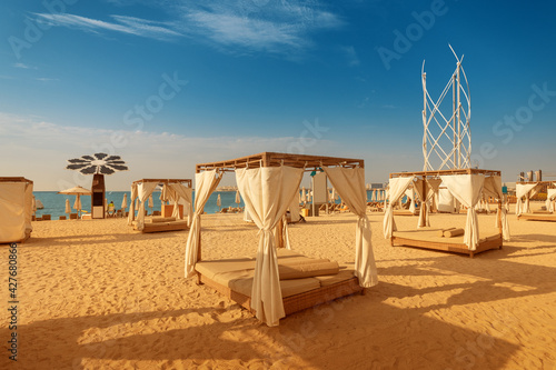 Photography canopy with curtains and parasol sunbeds waiting for tourists in Dubai Jumeirah beach resort