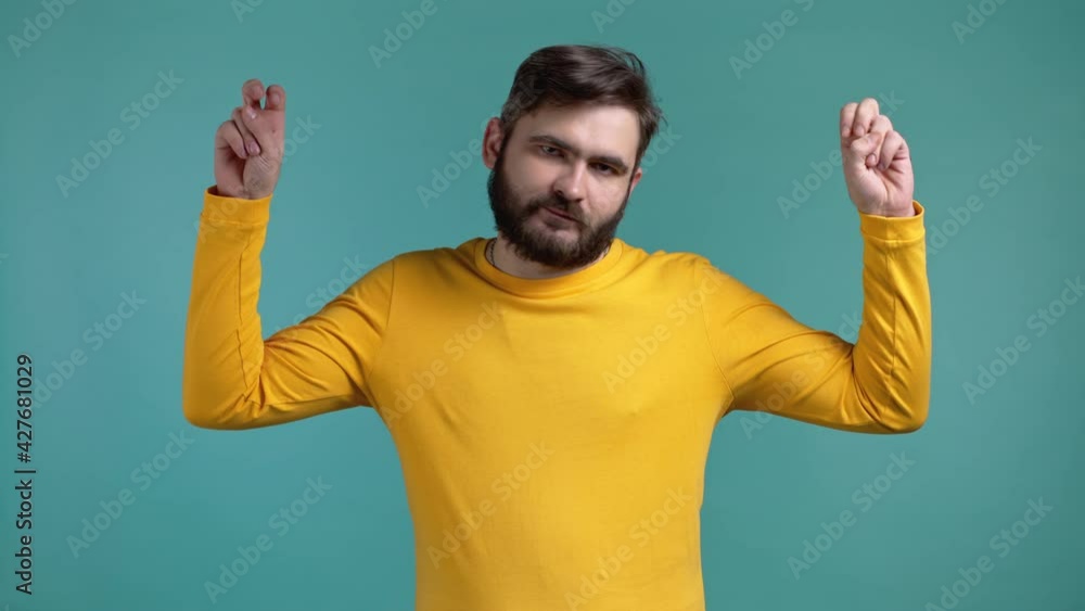 Handsome man showing with hands and two fingers air quotes gesture, bend fingers isolated on blue background. Guy in yellow wear. Not funny, irony and sarcasm concept. Handsome man showing with hands and two fingers air quotes gesture, bend fingers isolated on blue background. Guy in yellow wear. Not funny, irony and sarcasm concept.