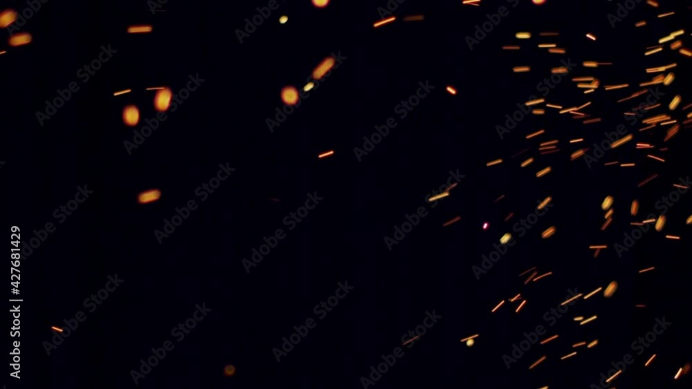 Burning red-hot sparks rise from large fire in the night sky, in slow motion. Burning red-hot sparks rise from large fire in the night sky, in slow motion.