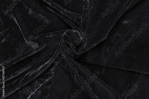 Colored black textile satin fabric folded in folds and waves with highlights and texture