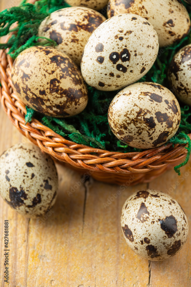 Obraz premium Aerial view of basket with quail eggs on wooden table with two eggs, selective focus, vertical, with copy space