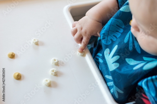 Fotografía Baby using pointer finger to drag a cereal puff to edge of tray: baby led weanin