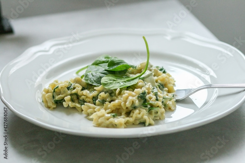 Pasta with Mascarpone cheese sauce and spinach on a white plate with a silver fork