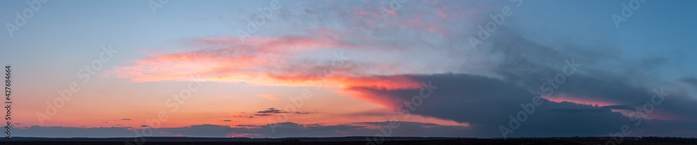Dramatic gloomy panorama of bright saturated sunset with large dark clouds