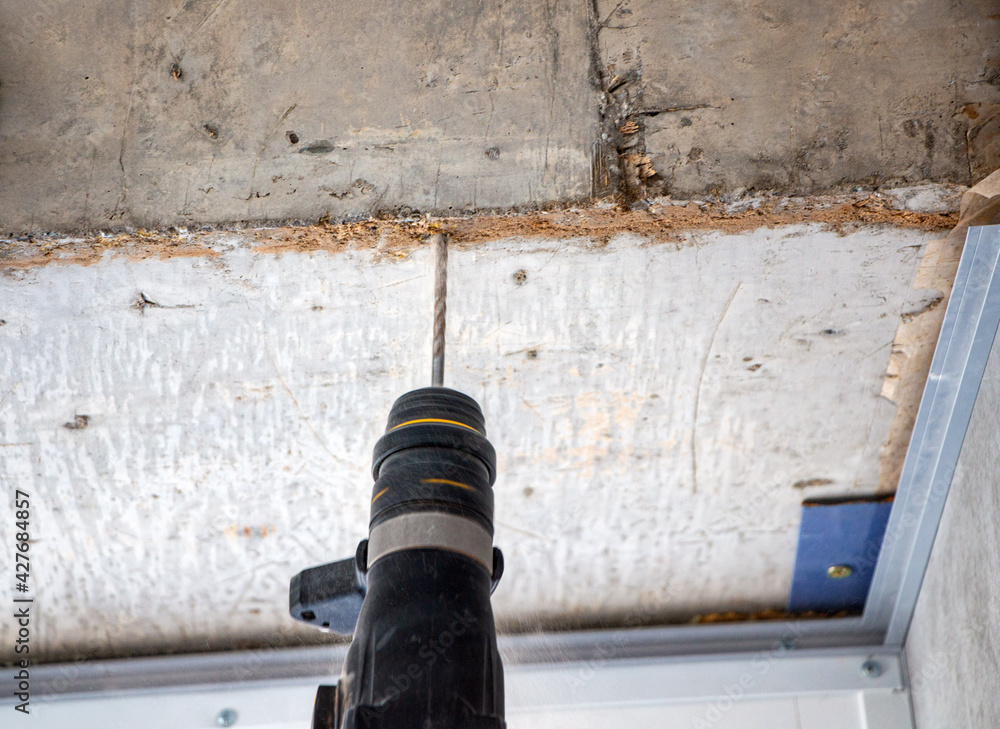 male hands of construction worker drills hole in concrete with hand