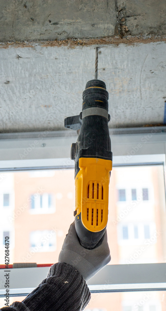 male hands of construction worker drills hole in concrete with hand