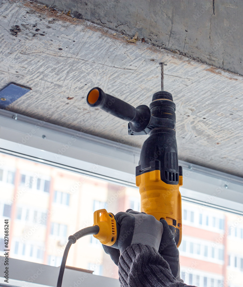 male hands of construction worker drills hole in concrete with hand