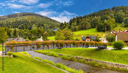 Panoramic view of Beskidy Mountains surrounding Szczyrk mountain resort with bridge over Zylica creek in Beskidy Mountains in Silesia region of Poland