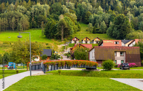 Fototapeta Naklejka Na Ścianę i Meble -  Panoramic view of Beskidy Mountains surrounding Szczyrk mountain resort with bridge over Zylica creek in Beskidy Mountains in Silesia region of Poland