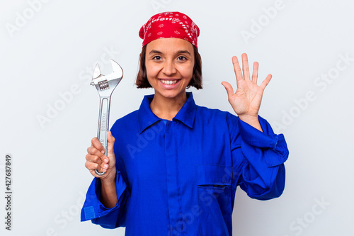 Young mechanical woman holding a key isolated smiling cheerful showing number five with fingers.
