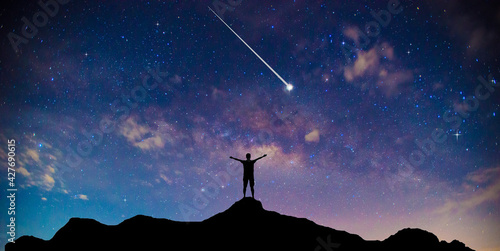 Amazing beautiful night sky and stars with meteor or shooting star as background.Traveler Man Silhouette Stand Top Mountain.
