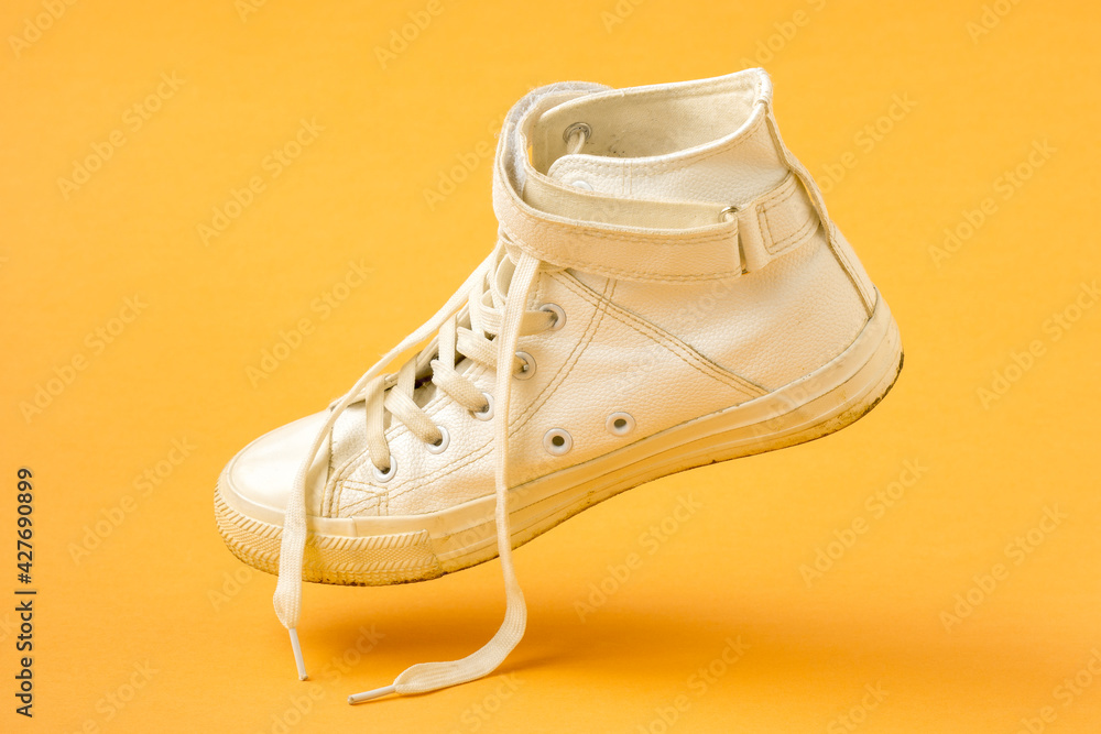 White shoe falling on the yellow background White shoe falling on the yellow background