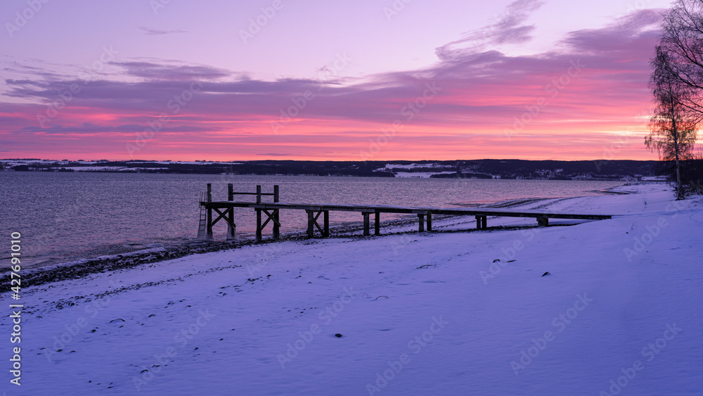 Pier by Lake Mjøsa in Totenvika at winter by sunrise.
