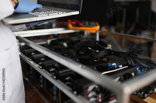 Master checking cryptocurrency mining rig using graphic cards closeup